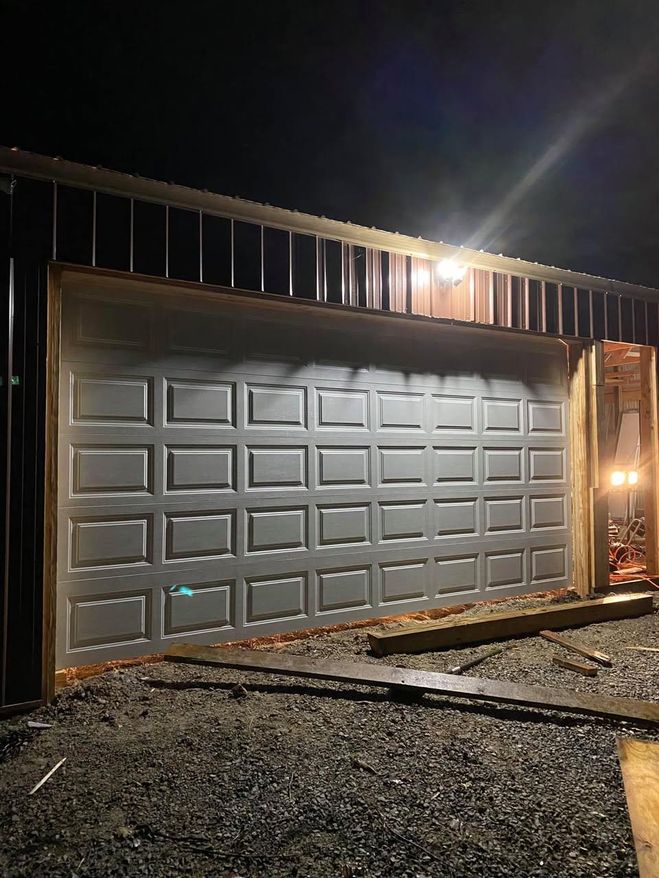 Bronze raised-panel garage door photographed at night after installation