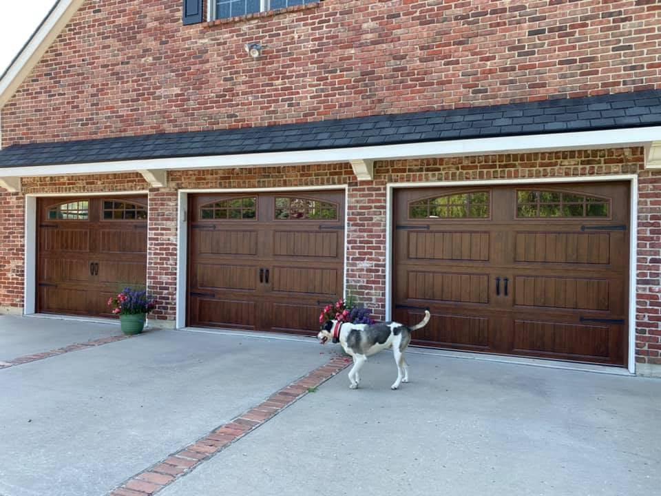 Carriage-style wood-grain garage doors installed on a brick home in the Kansas City metro