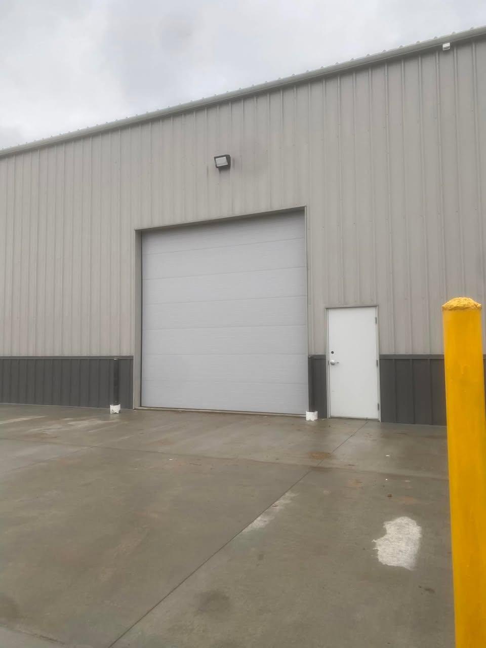 White commercial sectional door and man door on a warehouse exterior