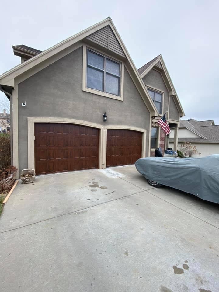 Dark walnut double garage doors on a stucco home, installed near Kansas City