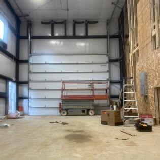 Garage door installation in progress with insulated panels and scissor lift
