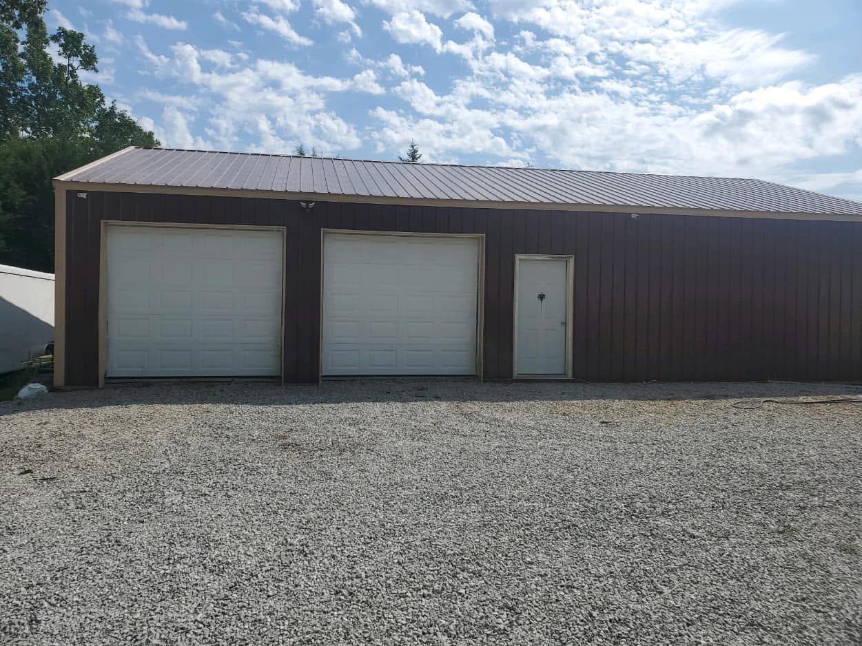 Pole barn with two new white overhead doors and walk-in entry door
