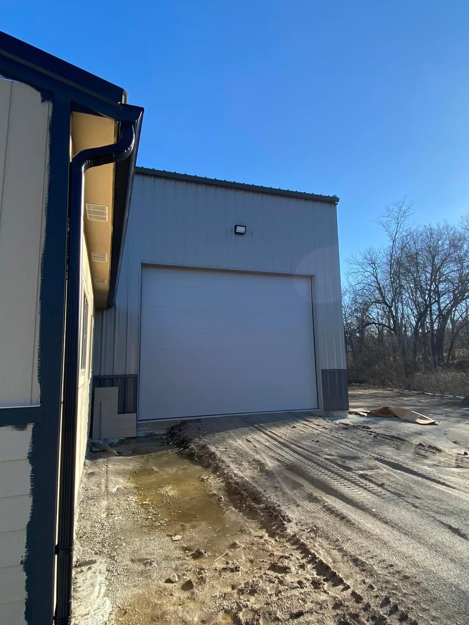 White insulated sectional door installed on a blue-trim metal building